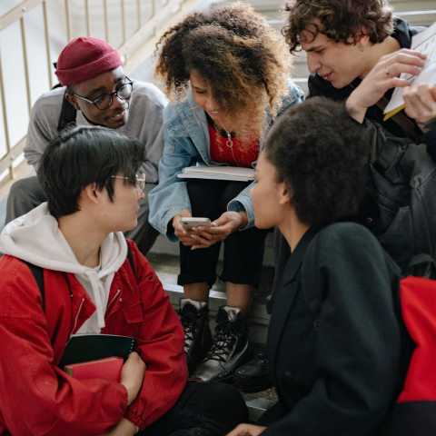 Un gruppo di giovani si confrontano seduti sulle scale di una scuola