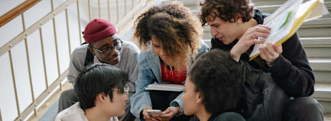 Un gruppo di giovani si confrontano seduti sulle scale di una scuola
